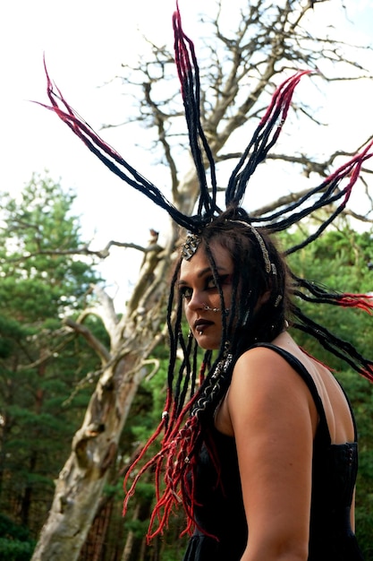 Jovem mulher caucasiana com cabelo punk preto e vermelho posando na floresta