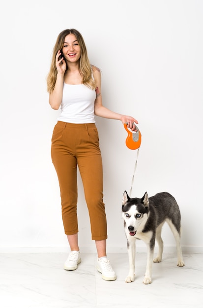 Jovem mulher caucasiana com cachorro sobre parede isolada