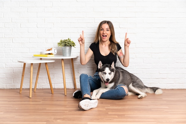 Foto jovem mulher caucasiana com cachorro sobre parede isolada