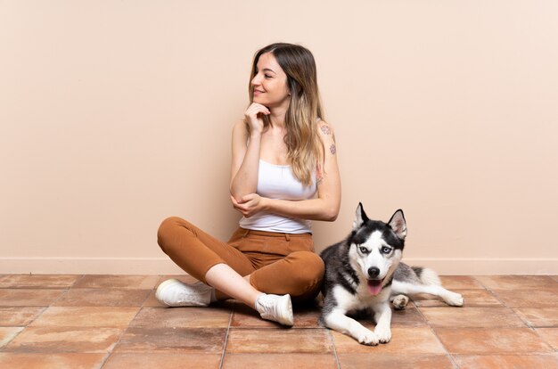 Jovem mulher caucasiana com cão sobre uma parede isolada