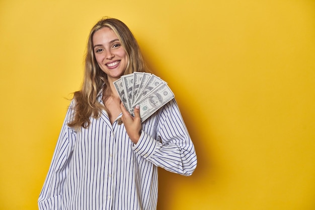 Jovem mulher caucasiana com dinheiro feliz sorridente e alegre