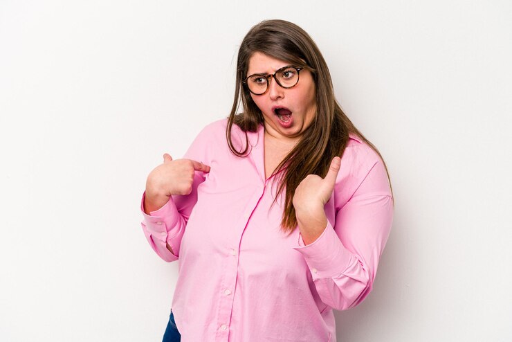 Foto jovem mulher caucasiana com excesso de peso isolada em fundo branco surpreendeu apontando com o dedo sorrindo amplamente