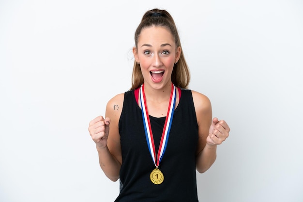 Jovem mulher caucasiana com medalhas isoladas no fundo branco comemorando uma vitória na posição de vencedor