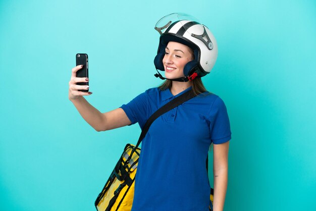 Jovem mulher caucasiana com mochila térmica isolada no fundo branco, fazendo uma selfie