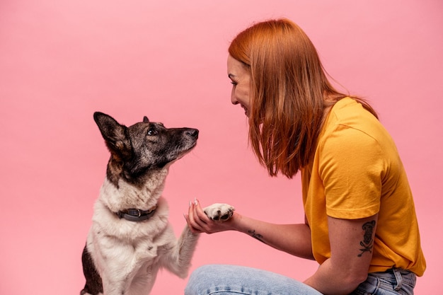 Jovem mulher caucasiana com seu cachorro isolado no fundo rosa