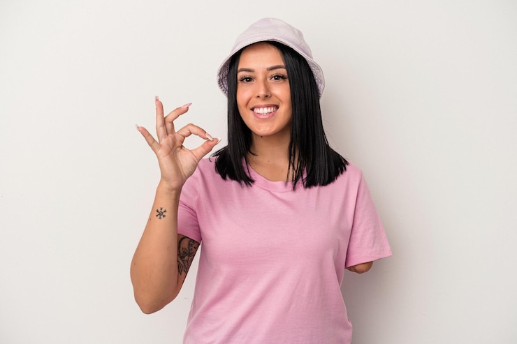Foto jovem mulher caucasiana com um braço isolado no fundo branco, alegre e confiante, mostrando um gesto de ok.
