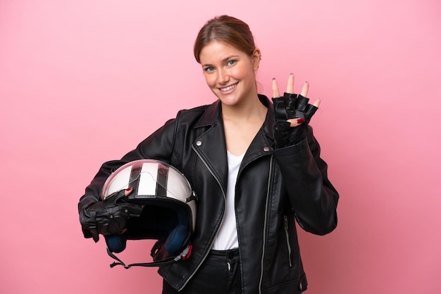 Jovem mulher caucasiana com um capacete de moto isolado em fundo rosa feliz e contando quatro com os dedos