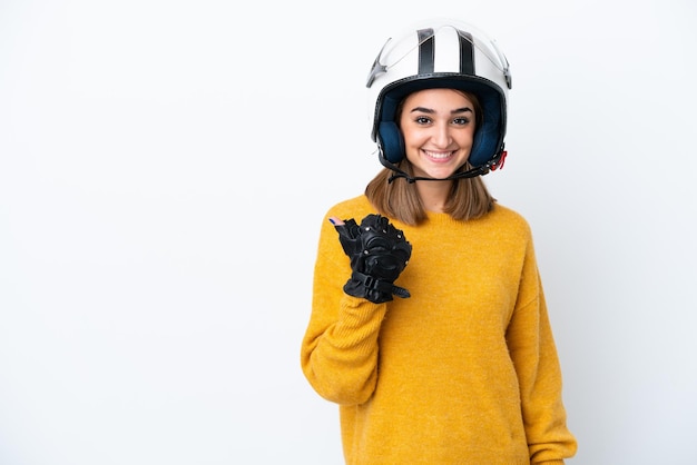 Jovem mulher caucasiana com um capacete de motociclista isolado no fundo branco apontando para o lado para apresentar um produto