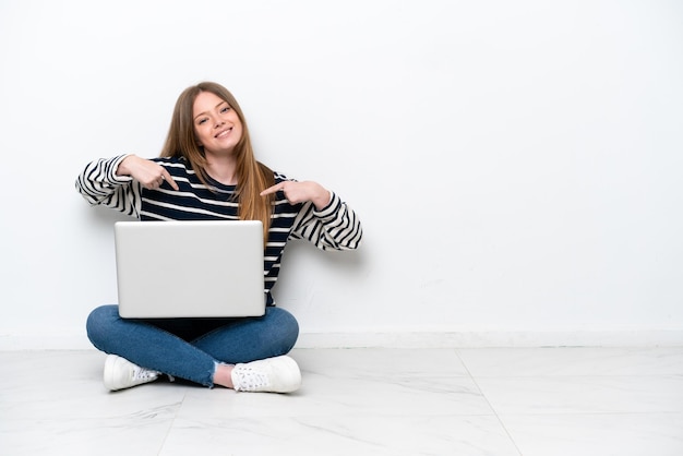 Jovem mulher caucasiana com um laptop sentada no chão