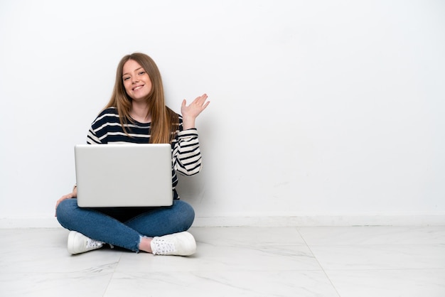 Jovem mulher caucasiana com um laptop sentada no chão