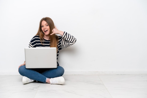 Jovem mulher caucasiana com um laptop sentada no chão