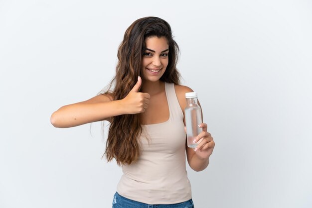 Jovem mulher caucasiana com uma garrafa de água isolada no fundo branco, dando um polegar para cima gesto