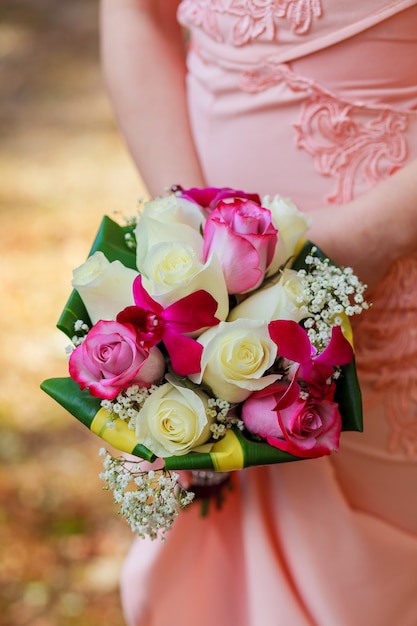 Jovem mulher caucasiana com vestido de renda rosa segura um buquê com flores e rosas cor de rosa do jardim nas mãos