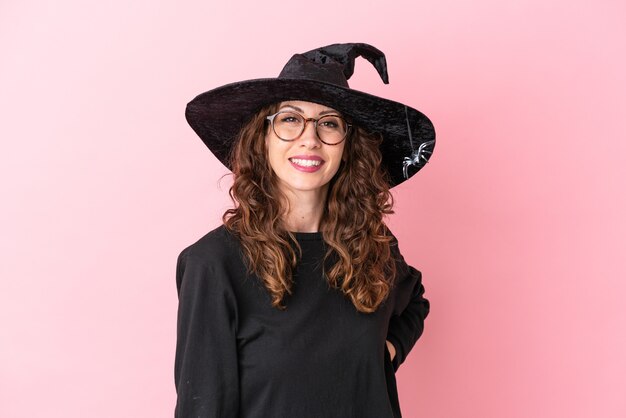 Jovem mulher caucasiana comemorando o dia das bruxas isolada em um fundo rosa com óculos e feliz