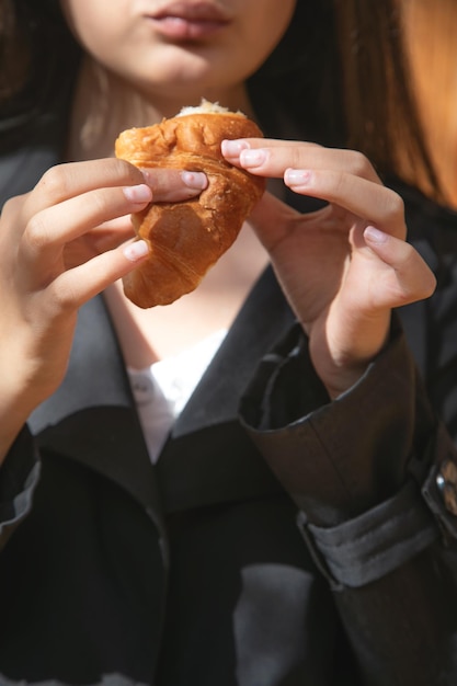 Jovem mulher caucasiana comendo croissant