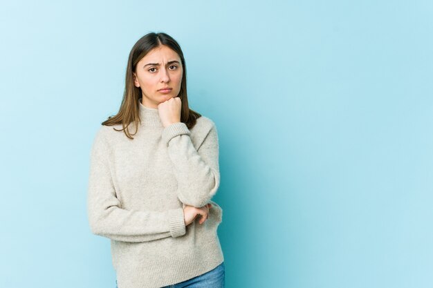 Jovem mulher caucasiana, desconfiada, incerta, examinando você.