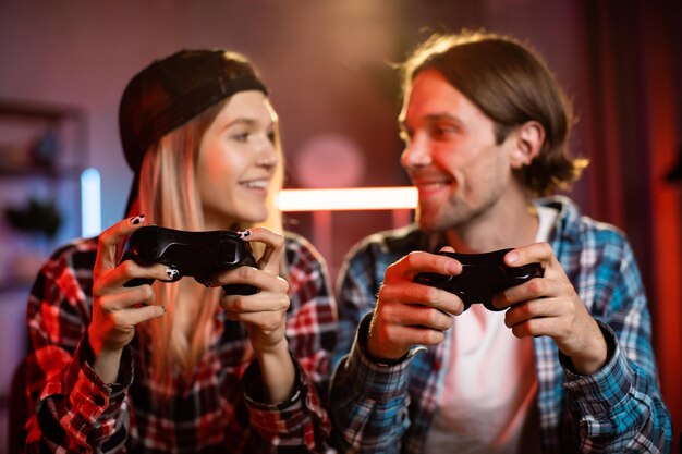 Foto jovem mulher caucasiana e homem bonito sentados juntos à mesa e jogando videogame