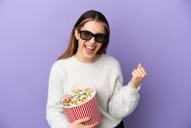 Foto jovem mulher caucasiana em azul com óculos 3d e segurando um grande balde de pipocas