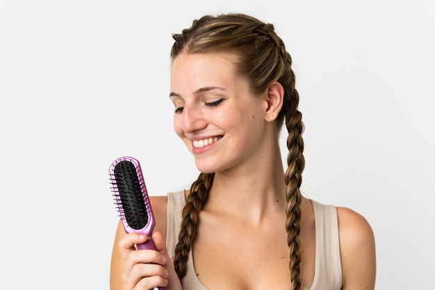 Foto jovem mulher caucasiana em branco com pente de cabelo e olhando para ele