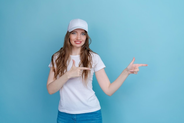 Jovem mulher caucasiana em camiseta branca e jeans sorrindo alegremente apontando