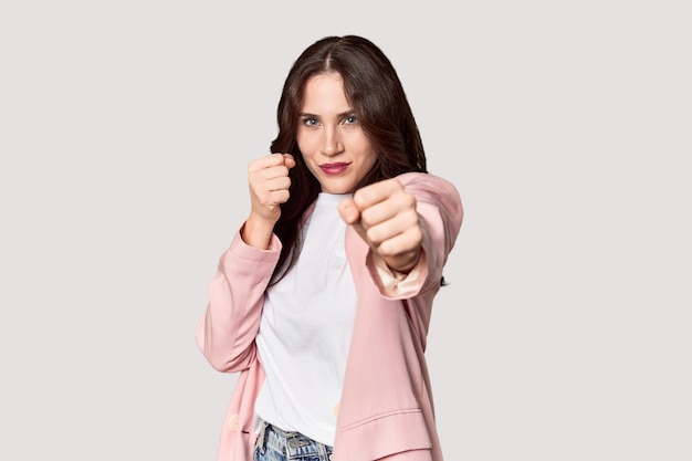Jovem mulher caucasiana em um estúdio jogando um soco de raiva lutando devido a uma discussão de boxe