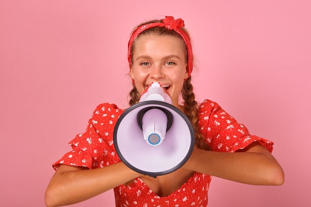 Jovem mulher caucasiana entusiástica com sorriso segura suportes de megafone no estúdio