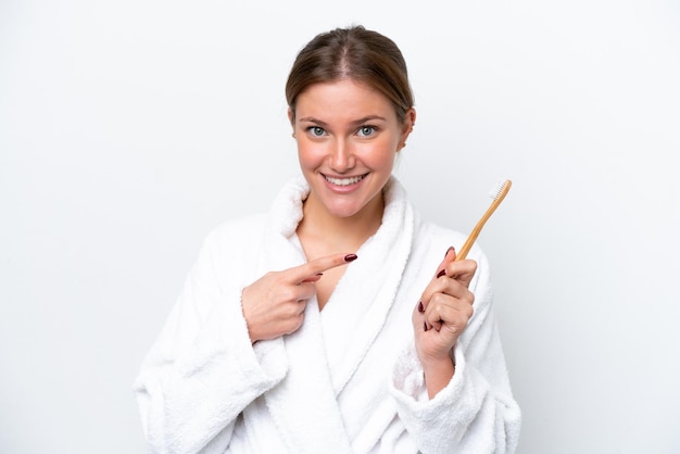 Jovem mulher caucasiana escovando os dentes isolados no fundo branco com expressão facial de surpresa