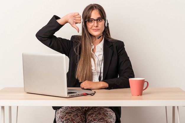 Jovem mulher caucasiana fazendo teletrabalho isolado no fundo branco, mostrando um gesto de antipatia, polegares para baixo. Conceito de desacordo.