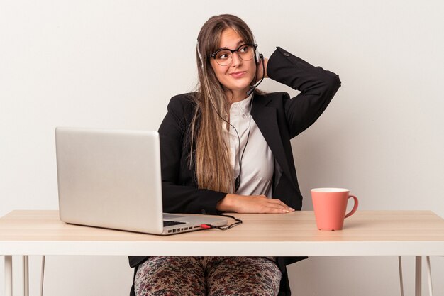 Jovem mulher caucasiana fazendo teletrabalho isolado no fundo branco, tocando a parte de trás da cabeça, pensando e fazendo uma escolha.