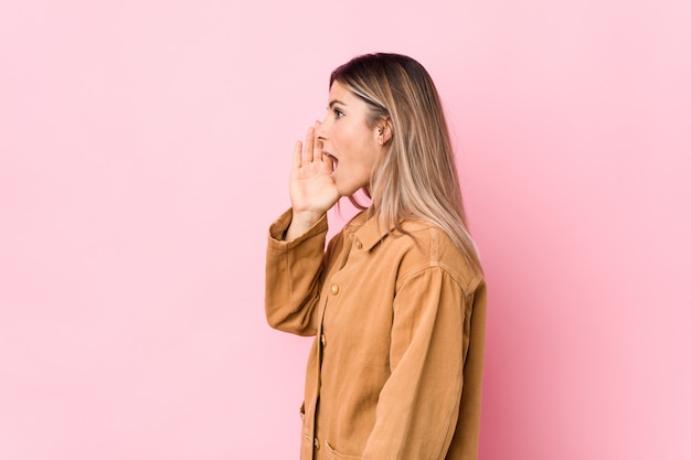 Foto jovem mulher caucasiana, gritando e segurando a palma da mão perto da boca aberta.