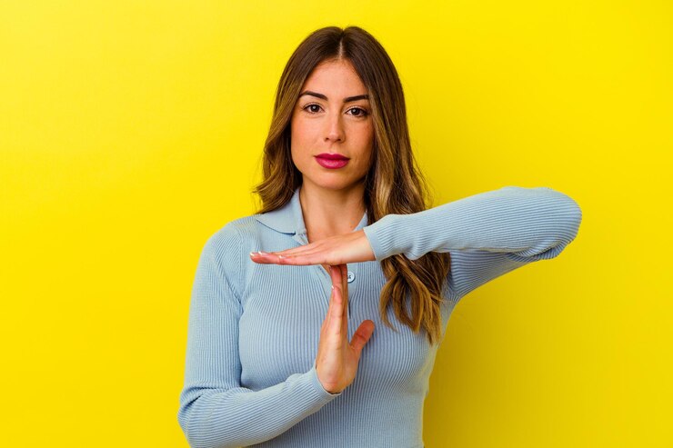 Foto jovem mulher caucasiana isolada em amarelo, mostrando um gesto de tempo limite.
