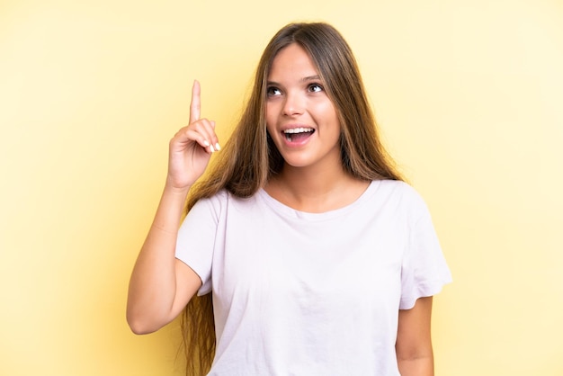 Jovem mulher caucasiana isolada em fundo amarelo com a intenção de perceber a solução enquanto levanta um dedo