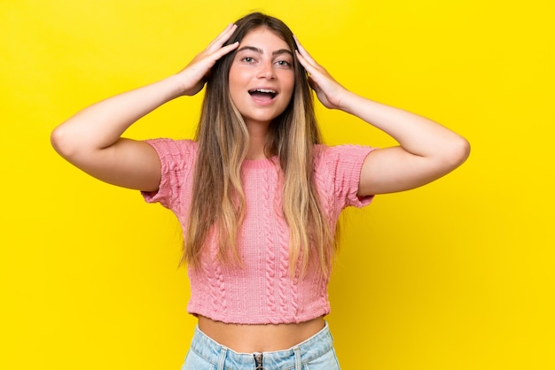 Jovem mulher caucasiana isolada em fundo amarelo com expressão de surpresa