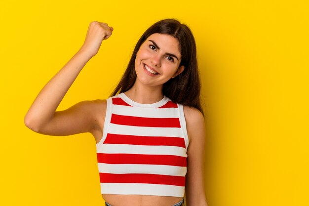 Jovem mulher caucasiana isolada em fundo amarelo, comemorando uma vitória, paixão e entusiasmo, expressão feliz.