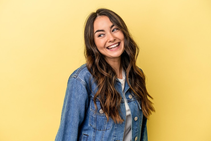 Foto jovem mulher caucasiana isolada em fundo amarelo ri e fecha os olhos se sente relaxada e feliz