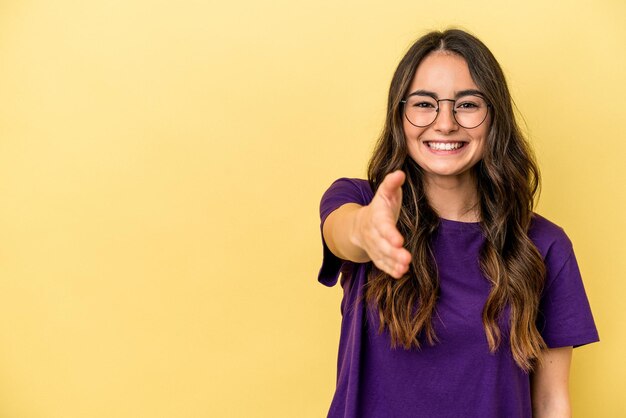 Jovem mulher caucasiana isolada em fundo amarelo sorrindo e levantando o polegar