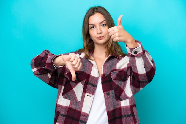 Foto jovem mulher caucasiana isolada em fundo azul fazendo bom sinal indeciso entre sim ou não