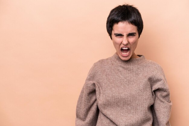 Jovem mulher caucasiana isolada em fundo bege gritando conceito de raiva muito irritado frustrado