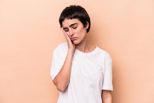 Jovem mulher caucasiana isolada em fundo bege que está entediada, cansada e precisa de um dia de relaxamento.