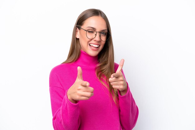 Jovem mulher caucasiana isolada em fundo branco apontando para a frente e sorrindo