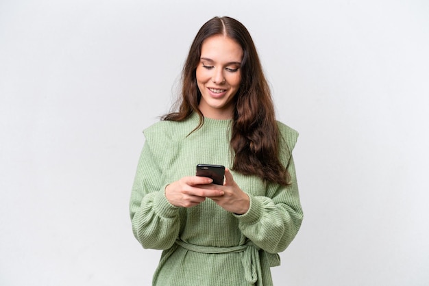 Jovem mulher caucasiana isolada em fundo branco enviando uma mensagem com o celular