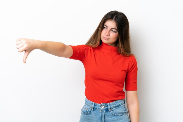 Jovem mulher caucasiana isolada em fundo branco mostrando o polegar para baixo com expressão negativa