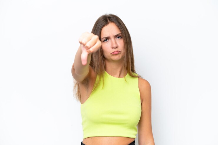 Foto jovem mulher caucasiana isolada em fundo branco mostrando o polegar para baixo com expressão negativa
