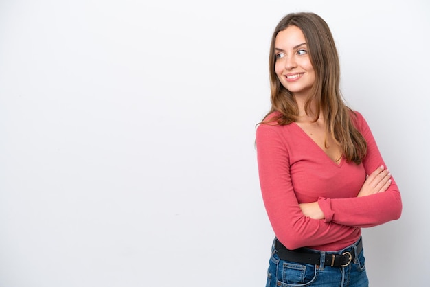 Jovem mulher caucasiana isolada em fundo branco olhando para o lado e sorrindo