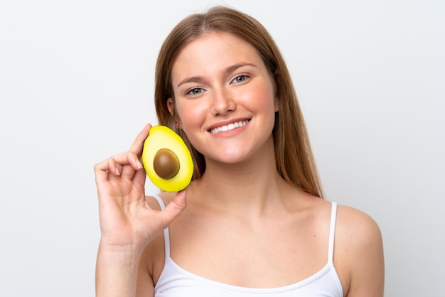 Jovem mulher caucasiana isolada em fundo branco segurando um abacate enquanto sorria Fechar o retrato