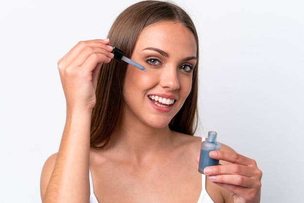 Jovem mulher caucasiana isolada em fundo branco segurando um soro enquanto sorri Retrato em close-up