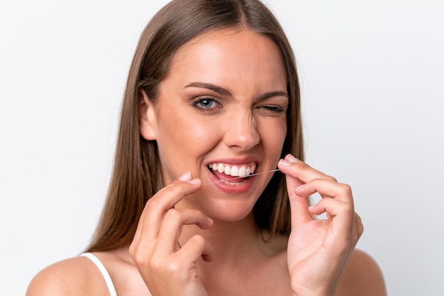 Jovem mulher caucasiana isolada em fundo branco usando fio dental com expressão feliz Feche o retrato