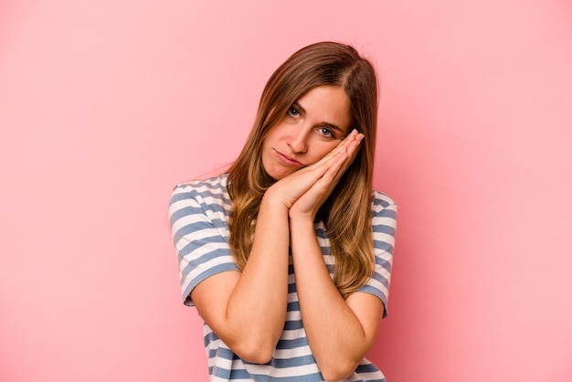 Jovem mulher caucasiana isolada em fundo rosa bocejando mostrando um gesto cansado cobrindo a boca com a mão