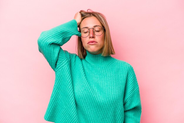 Jovem mulher caucasiana isolada em fundo rosa cansada e com muito sono, mantendo a mão na cabeça