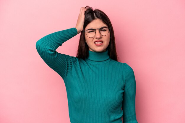 Jovem mulher caucasiana isolada em fundo rosa cansada e com muito sono, mantendo a mão na cabeça